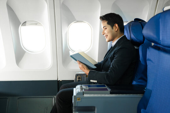 Young Asian executive excels in first class, multitasking with digital tablet, laptop and smartphone. Travel in style, work with grace. - Powered by Adobe