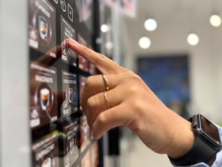 close up of a hand touching the screen of a vending machine in the workplace hub