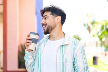 Handsome Arab man at outdoors holding a take away coffee