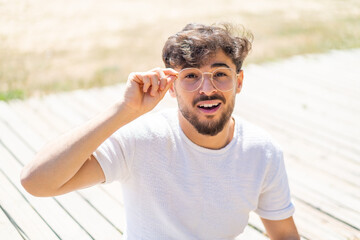 Handsome Arab man at outdoors With glasses and frustrated expression