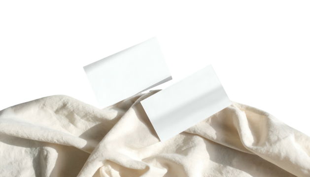 Two blank rectangular cards resting on a crumpled, light-colored fabric against a black background