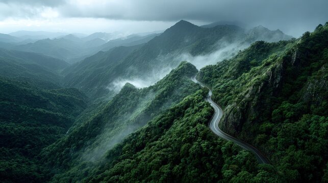 Overhead drone shot of a winding mountain pass scenic landscape with fog drifting between the peaks