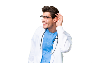 Young doctor man over isolated background listening to something by putting hand on the ear