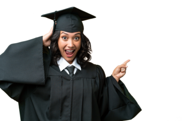 Young university graduate Argentinian woman over isolated background surprised and pointing finger to the side