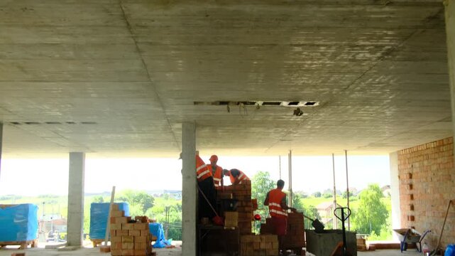 Inspector points at construction workers performing tasks. Builders follow instructions of manager and implement plan standing in unfinished building