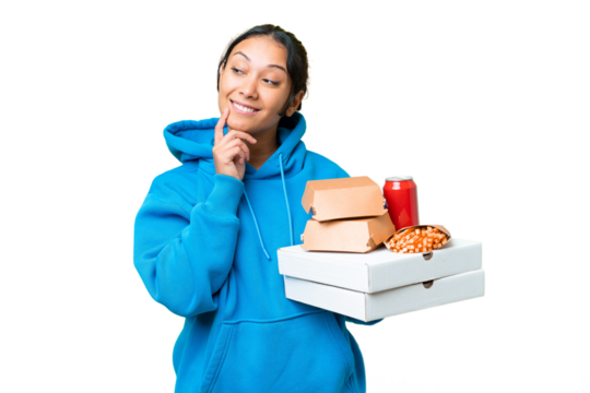 Young Uruguayan woman holding pizzas and burgers over isolated chroma key background thinking an idea while looking up