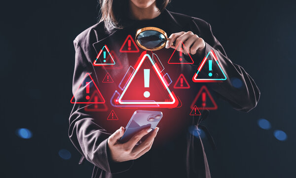Woman analyzing smartphone with magnifying glass and warning symbol holograms floating in air, concept of cybersecurity threat detection alert system.