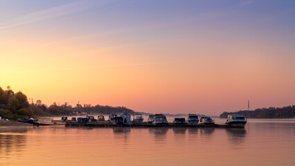 Fototapeta premium Boats on the river stand at the pier in the morning. Autumn foggy morning.