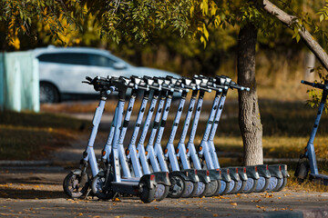 Row of Rental Escooters parked on a sidewalk on an Autumn City Street