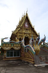 Fototapeta premium An intricately designed wooden temple nestled amidst verdant trees. The temple's architecture is striking, with gold accents that glisten under the sunlight