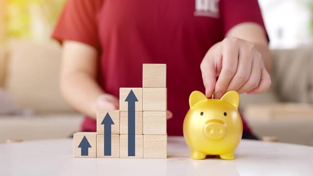 Hand putting a coin into a golden piggy bank with a growing chart and target goal in the background, concept of saving money for future and financial planning.