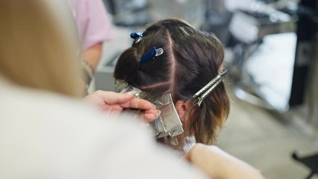 Stylist applies hair dye to client hair in professional salon with beauty procedures hairstyle care fashion style healthy hair services and modern appearance makeover