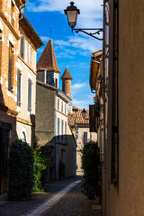 Fototapeta premium Bell Tower of Saint-Pierre Church Seen from a Narrow Street in the Historic Center of Auvillar