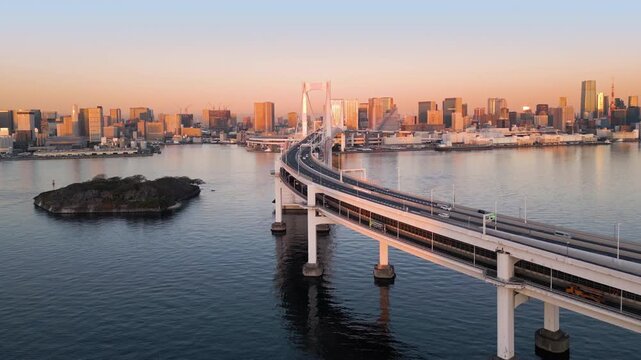 tokyo city skyline aerial shot drone at sunrise,view of the bay and waterfront,rising up over the rainbow bridge landmark at dawn,high rise modern buildings and business district in the background