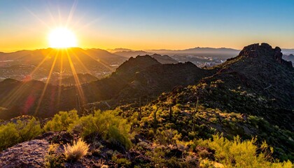 Mountainous desert landscape at sunset; radiating golden sunlight