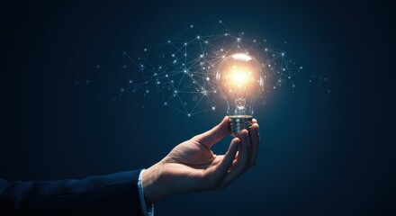 Hand holding glowing incandescent light bulb with digital particles exploding outwards against dark blue background