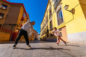 Male dancers performing street dance on cobblestone city street