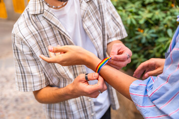 Man tying rainbow bracelet on another's wrist
