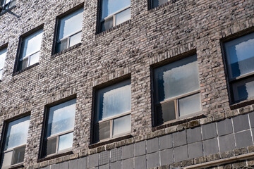 An old brick building with a classic window and the reflection of the sky