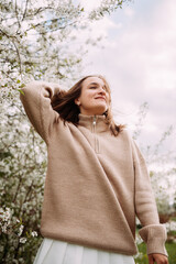 A girl in a sweater against a backdrop of blossoming trees 7288.