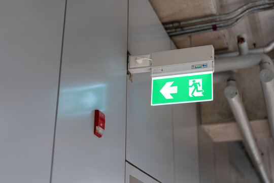 Fire escape route exit sign, lighting banner is glowing in green light that installed at building interior. Transportation sign object.