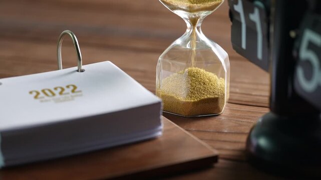 Time Management Concept with Hourglass and 2022 Calendar on Wooden Desk