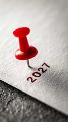 Red pin marks year 2027 on white paper