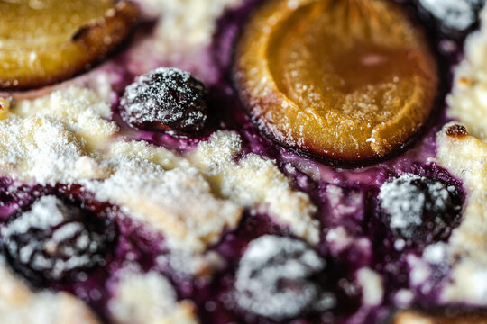 Background textured cheesecake, tart or quiche with blueberries and plums. Close-up.