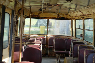 Fototapeta premium Empty and Forgotten: Rusty Interior of an Abandoned Vintage Bus with Red Seats