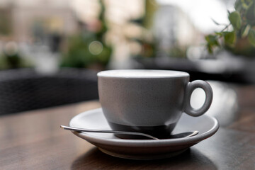 Minimalist coffee cup on saucer with spoon outdoors