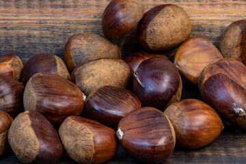castañas crudas sin pelas sobre fondo de madera oscura
