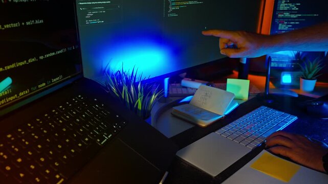 Programmer hand note coding workspace monitors. Creative developer scene with person writing on sticky note, multi-monitor setup with HTML Python code, ambient RGB lighting, modern technology concept