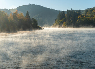 Autumn landscape with the Plitvice Lakes steaming in the morning and tourist boats sailing on Lake Kozjak
