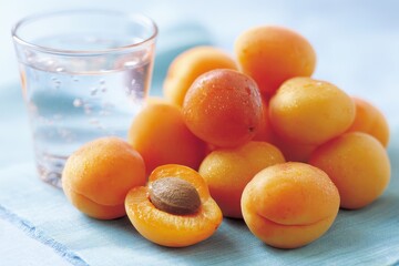 Fresh apricots piled near a glass of water for summer refreshment