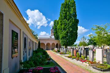 Wunderschön gestalteter und gepflegter  Friedhof mit einem roten Kiesweg zur Kapelle auf einem Friedhof in Rosenheim  © Blende8