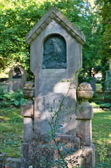 sehr alter stark verwitterter Grabstein mit Blumentöpfen aus Stein auf einem alten Friedhof in Landsberg Lech © Blende8