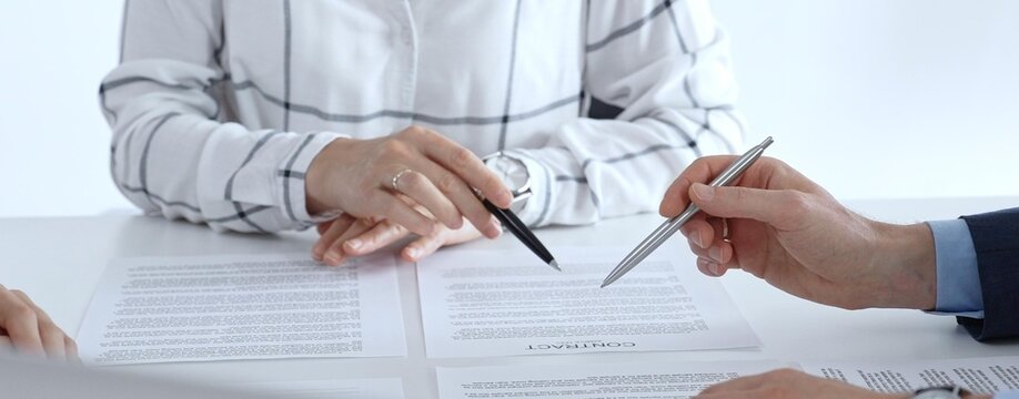 Business professionals or lawyers sitting at the desk in a bright office, reviewing and discussing contract papers. Teamwork concept