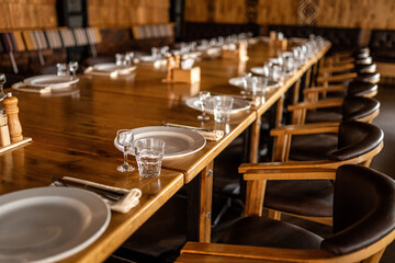 Long wooden restaurant table set for guests