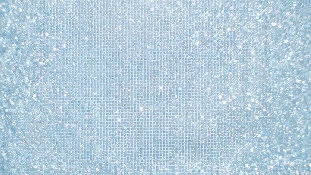 A close-up of a shimmering, light-blue surface with a grid-like pattern and scattered sparkles
