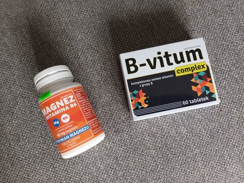Vitamins and supplements: bottle of Magnez B6 and box of B-vitum complex on a gray textured fabric surface