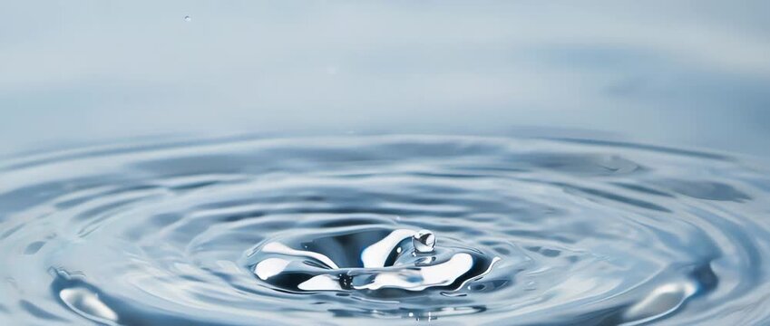 An extreme close-up in super slow motion of a water drop creating perfect ripples. Symbolizes purity, clean water resources, and environmental conservation.