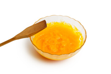 Closeup glass bowl with fresh homemade pumpkin puree and wooden spatula isolated on clean white background