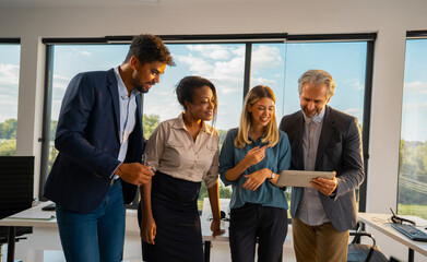 Diverse business professionals actively engaging in a group discussion, sharing ideas and collaborating on a project while reviewing information on a digital tablet in a modern office environment