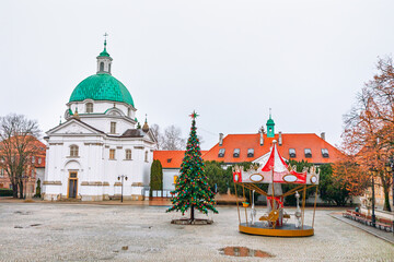  Church of Saint Casimir in Warsaw, Poland. Carousel and Christmas tree stand in the decorated New Town Market Square during the festive season