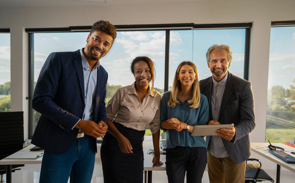 Diverse business professionals feeling confident, standing together in a bright contemporary office, representing teamwork, collaboration and success in a positive work environment - Powered by Adobe