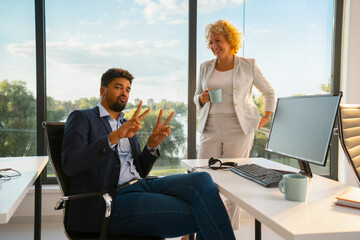 Diverse business colleagues interacting in a modern office, celebrating success and teamwork with a...