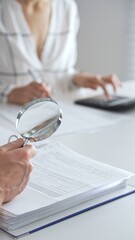 Groupe of professional accountants working together, using a magnifying glass and a calculators, to...