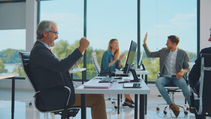 Business team members in a modern office celebrating success, achieving goals, and showing collaboration, high five gesture, and teamwork spirit during a busy workday