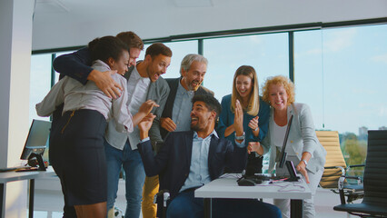 Diverse business team cheering and celebrating a successful achievement, finding excitement and joy during an important moment in a modern office workplace