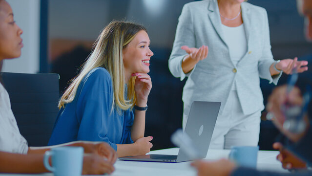 Businesswoman smiling during a dynamic office meeting, actively participating in discussion and contributing to team collaboration, showcasing professional engagement and positive work environment